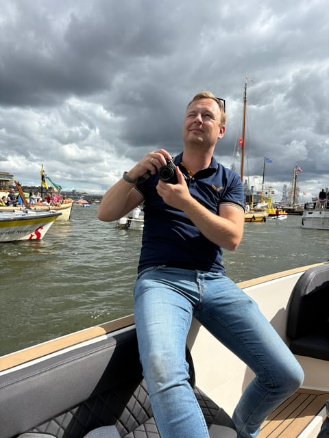Sander van Bueren op een boot met een camera in zijn handen, kijkend naar de horizon.